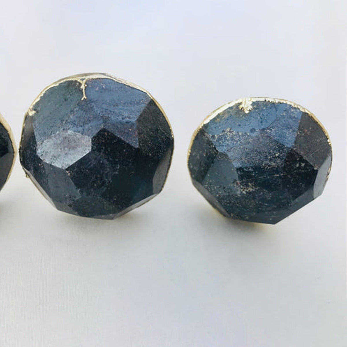 Two round knobs close, faceted grey stone against a white surface