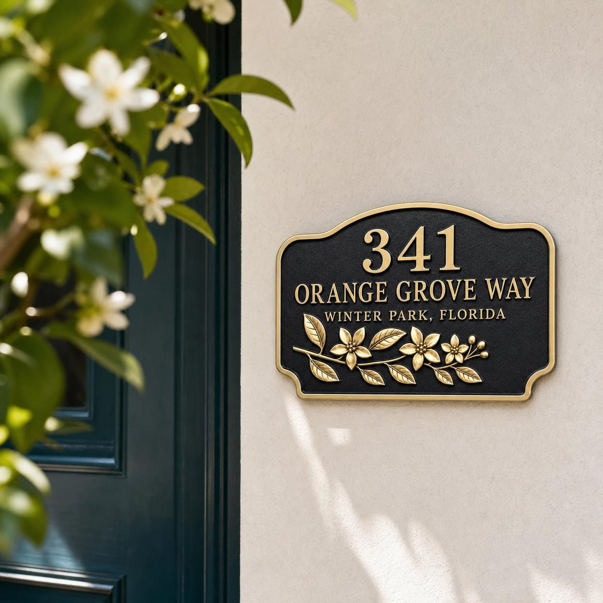 Orange Blossom name plate pictured on a pale wall beside greenery