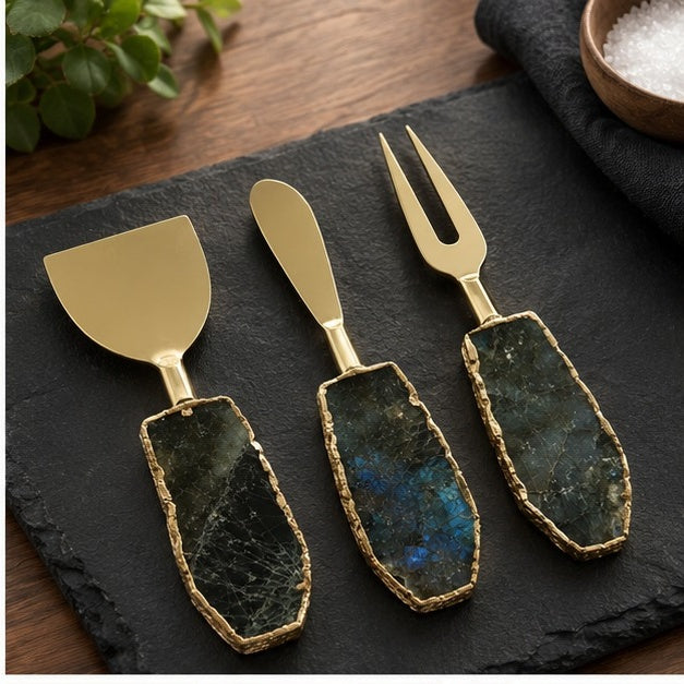 Labradorite cheese knife set of three on a black slate board with a wooden bowl