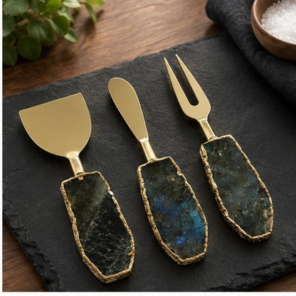 Labradorite cheese knife set of three on a black slate board with a wooden bowl