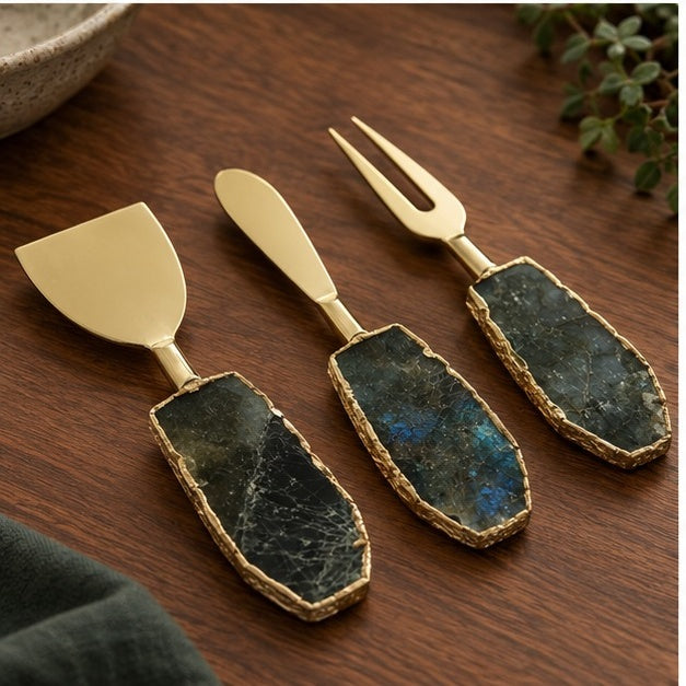 Labradorite cheese knives on cream linen beside a dark green napkin