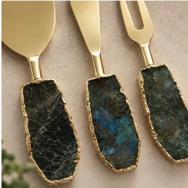 Labradorite cheese knives close up, blue flash in the dark stone handles against gold blades