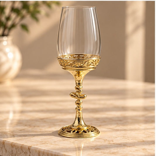 The Hammered wine glass, clear bowl set into a gold filigree collar with a twisted stem, on marble