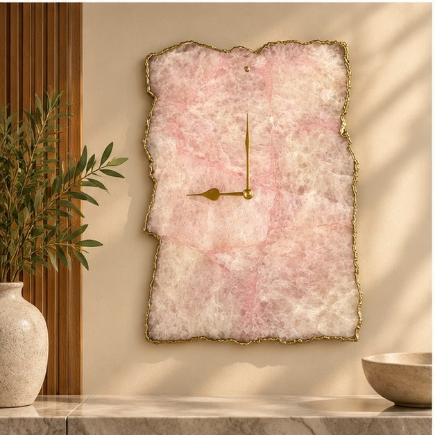 Rose quartz agate wall clock on a warm wall beside an olive plant