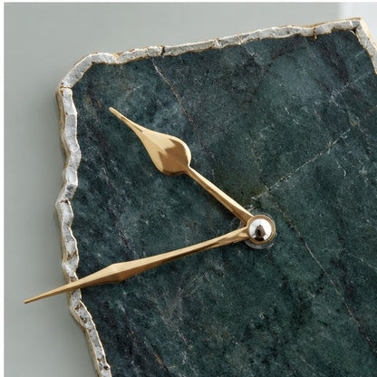 Close view of the green aventurine slab, its chipped pale edge and the gold hands