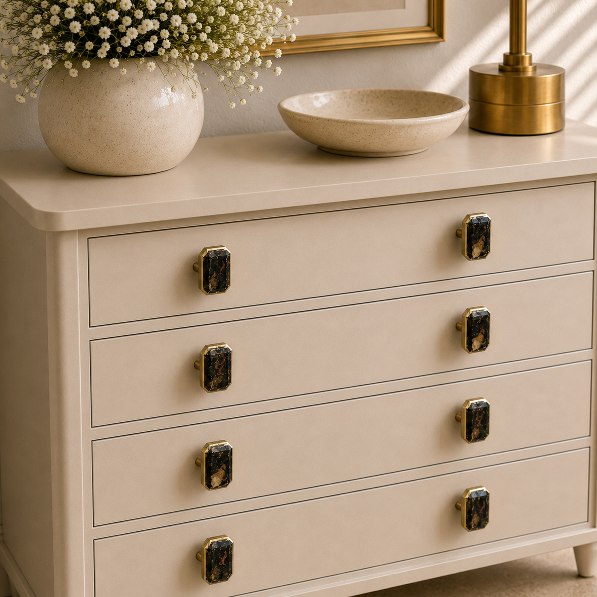 Eight dark pyrite knobs across four drawers of a cream chest of drawers