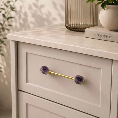 Amethyst tipped bar pull in gold on a cream drawer, fluted vase above