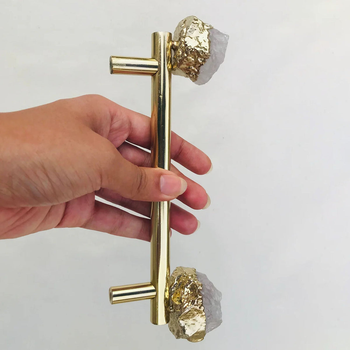 Gold bar pull upright in a hand, pale quartz caps top and bottom