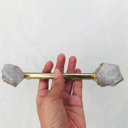 Hand holding the gold rod, milky white crystal ends either side