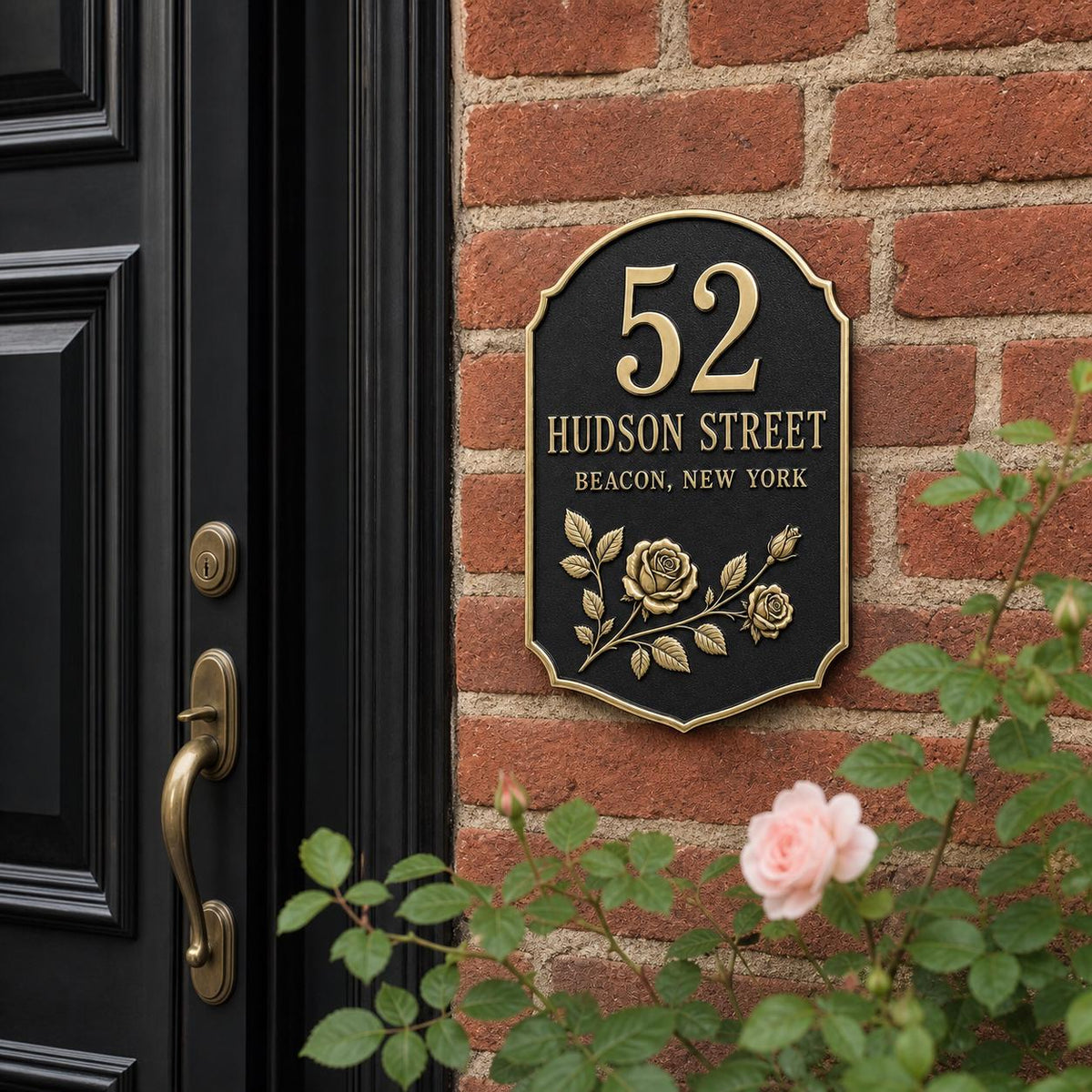 Rose address plaque pictured on a red-brick wall beside a dark entrance door