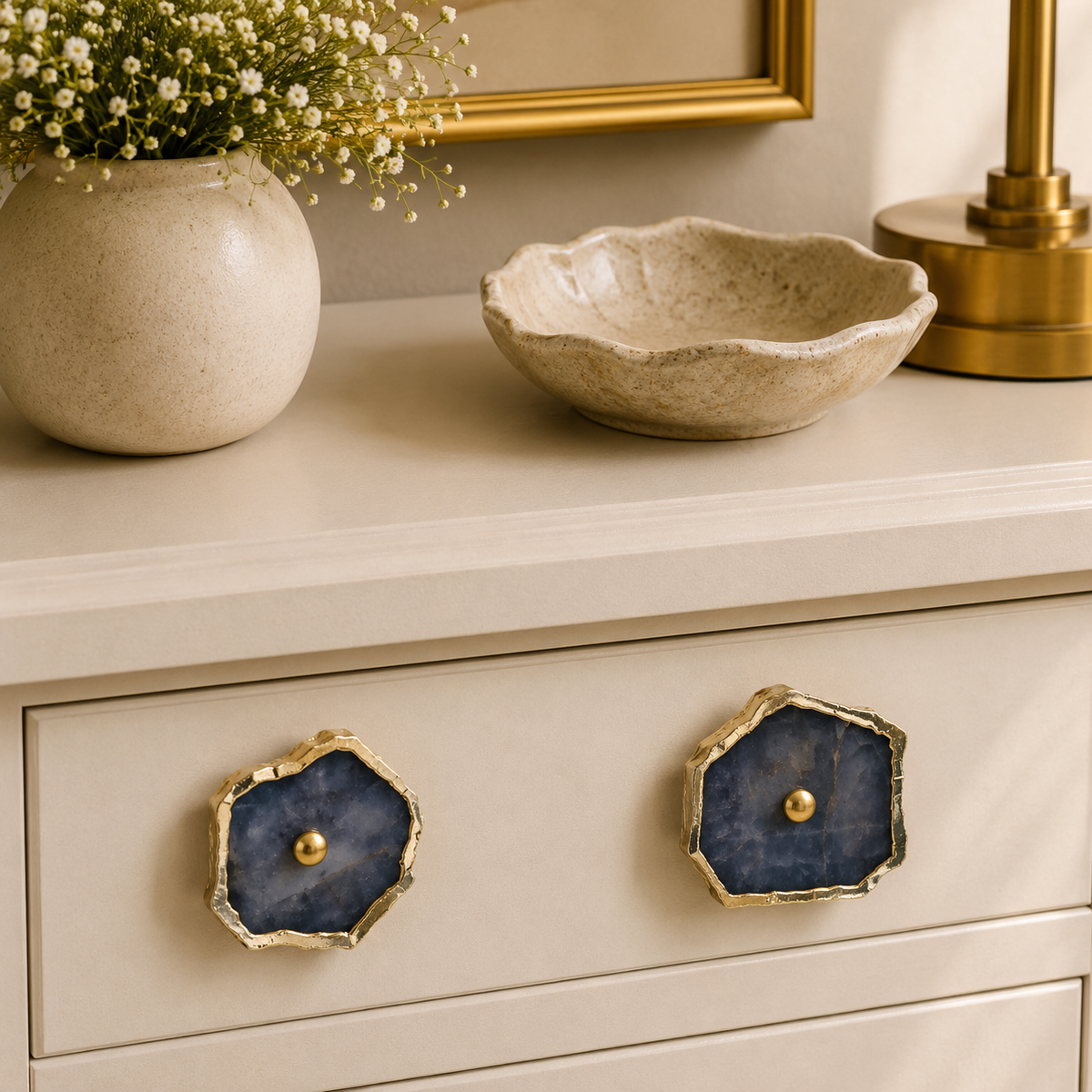 Two grey agate slice knobs on a cream drawer, brass lamp and bowl above