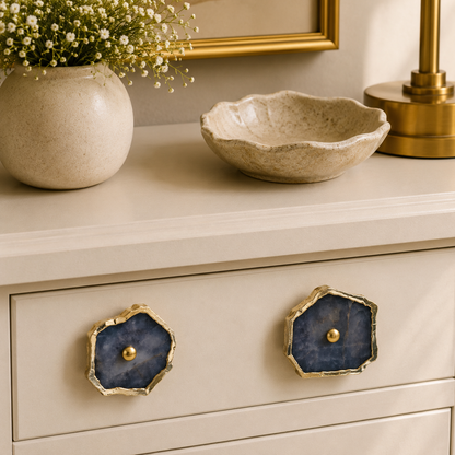 Two grey agate slice knobs on a cream drawer, brass lamp and bowl above