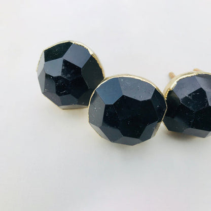 Three round obsidian knobs angled, black glass catching the light