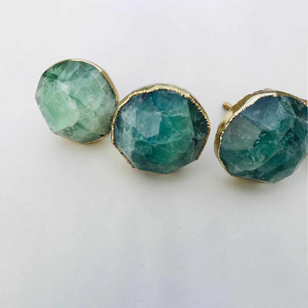 Three faceted knobs close, teal and mint banding through the fluorite