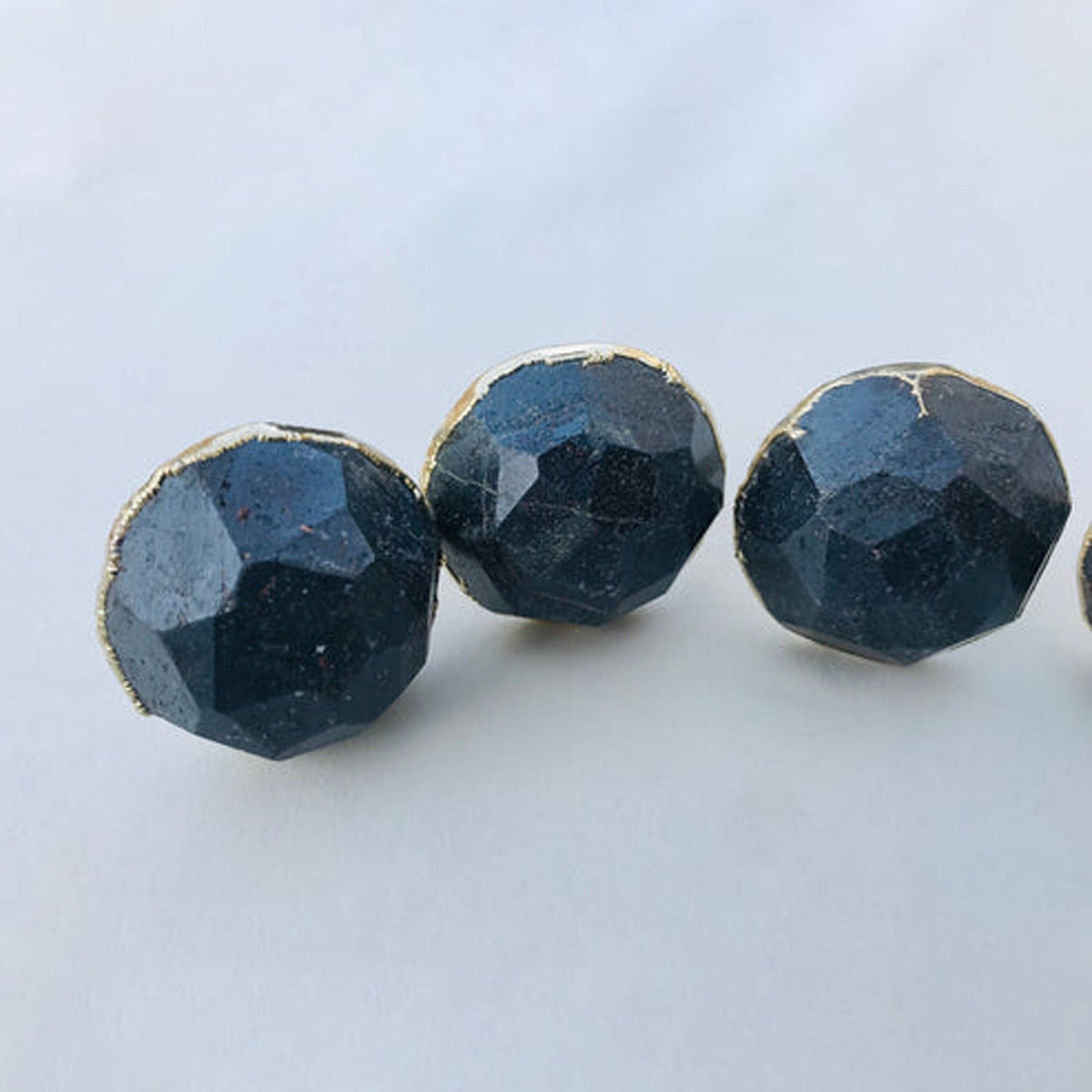 Three round knobs in a row, dark steel grey with pale gold rims
