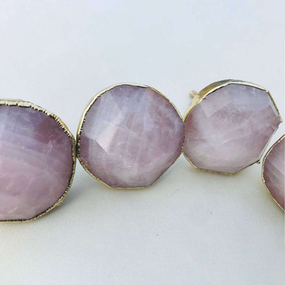 Four round knobs close, faceted lilac pink quartz inside gold edging
