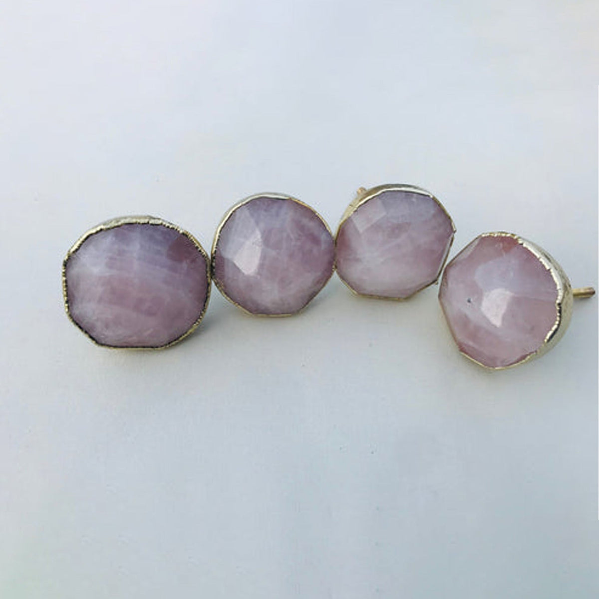 Four round rose quartz knobs in a row on pale grey, thin gold rims