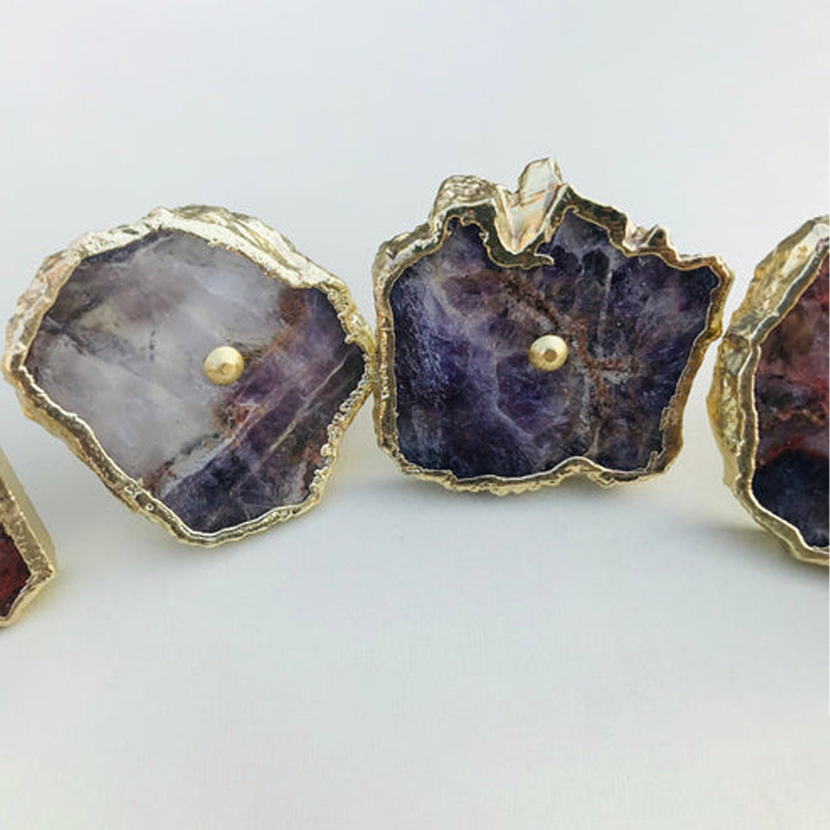 Three amethyst slices, purple and white banding under gold rims