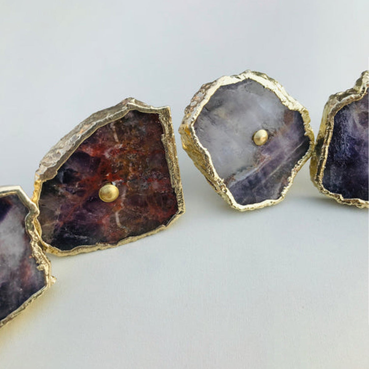 Four amethyst slices in a row, purple stone with rust red patches
