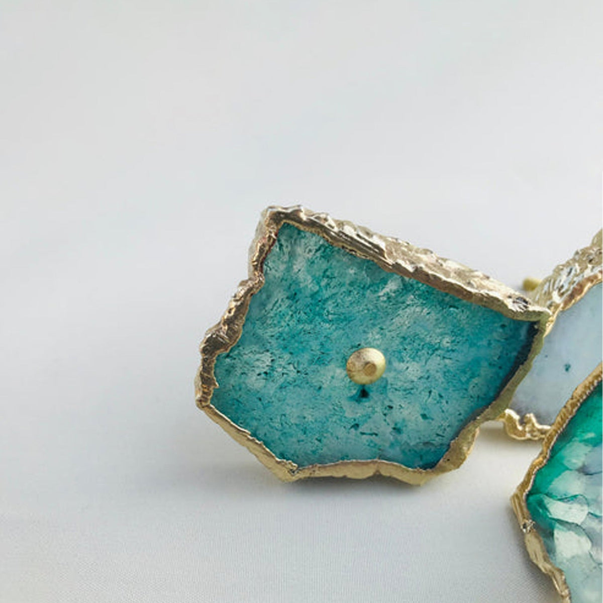 Two slices angled, teal agate banded with white under crusted gold