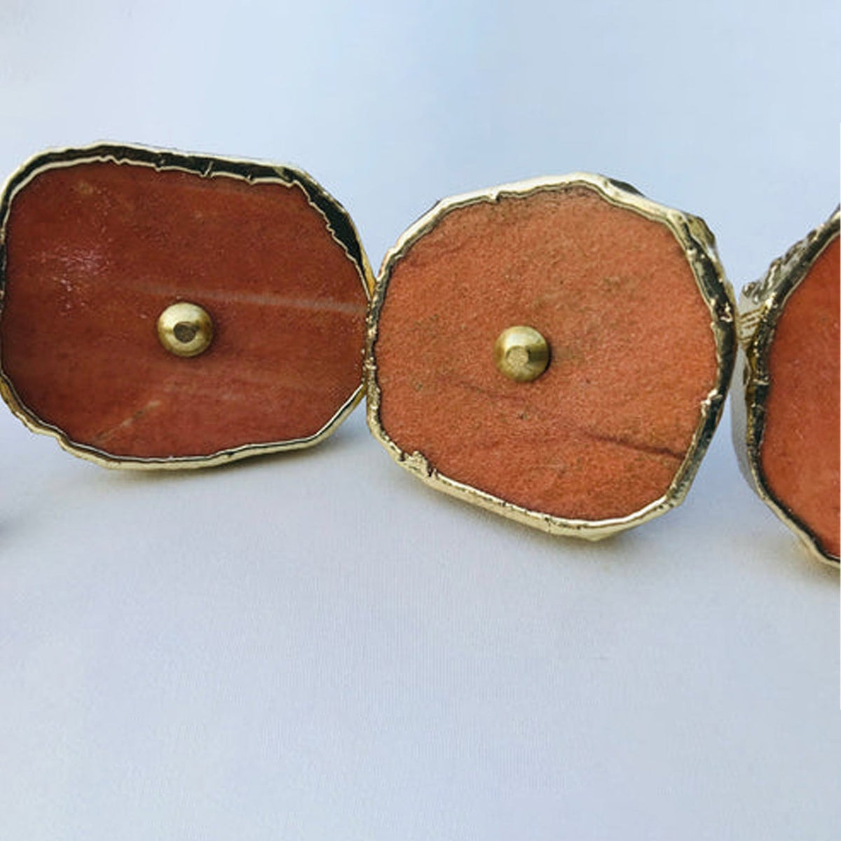 Three round slices angled, rust red faces each with a brass dome