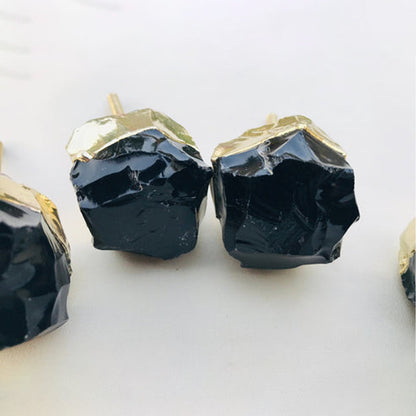 Three obsidian chunks close, glassy fractures under crumpled gold