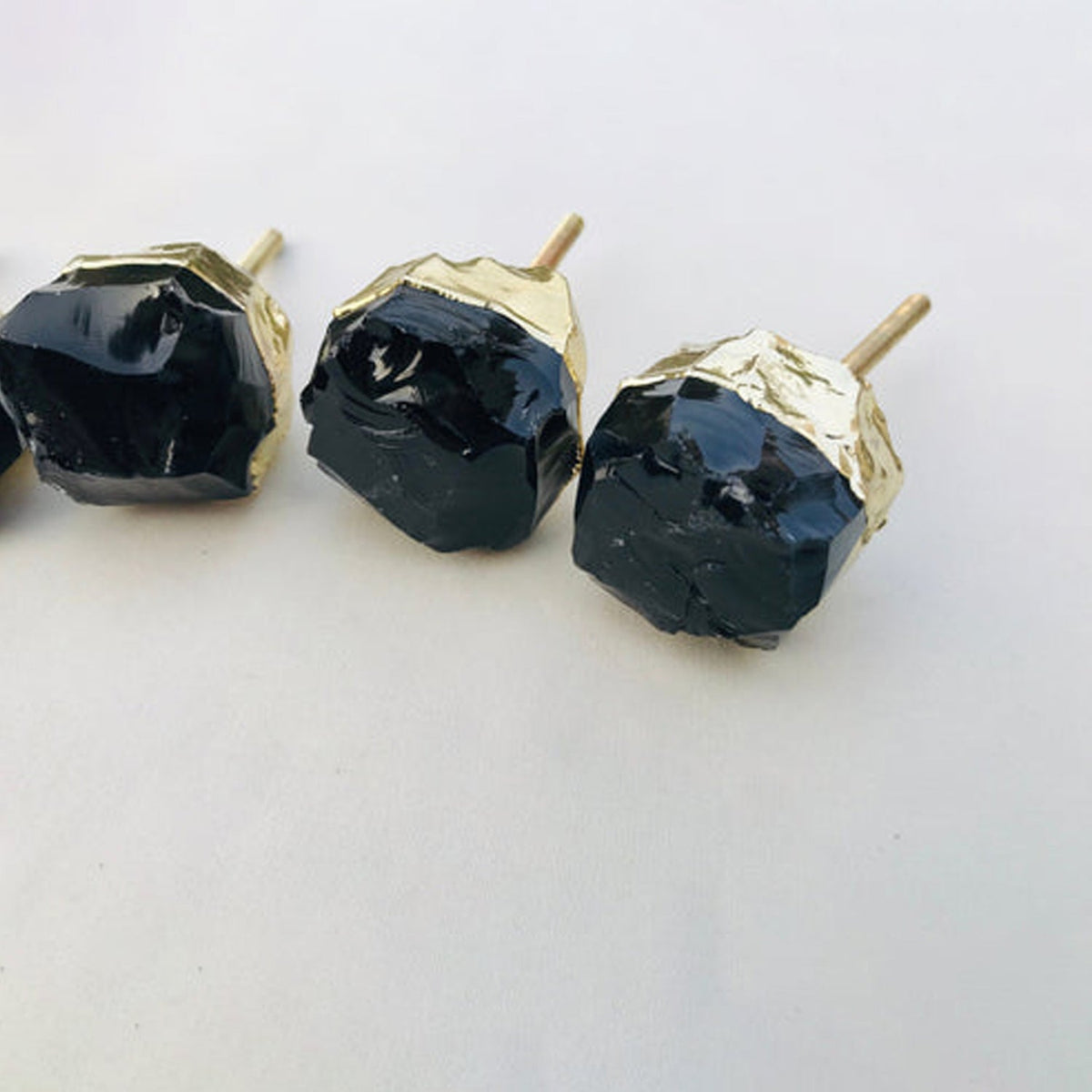 Three chunky obsidian knobs, brass posts angled towards the camera