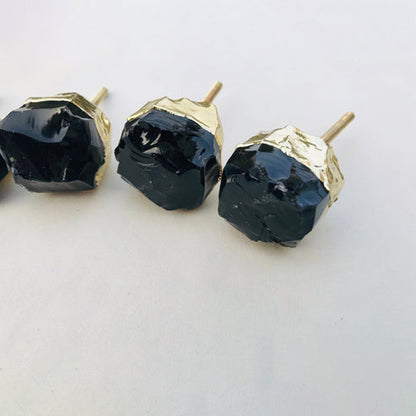 Three chunky obsidian knobs, brass posts angled towards the camera