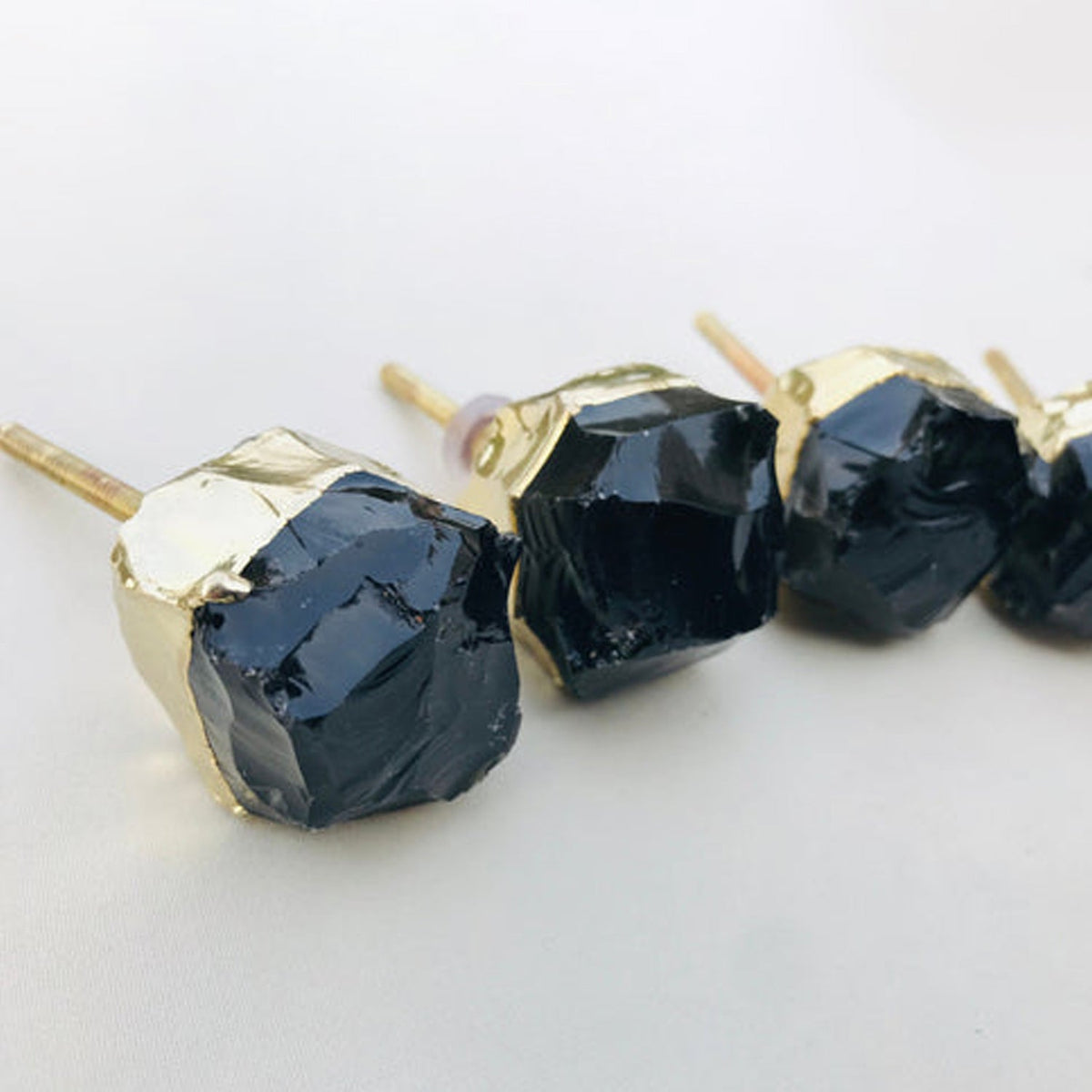 Four raw knobs in a row, uneven black glass inside thick gold