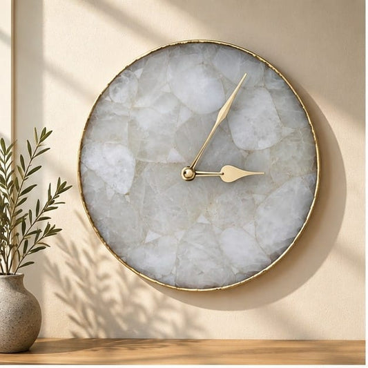 Large clear crystal agate circular wall clock with a gold rim, on a warm wall with greenery