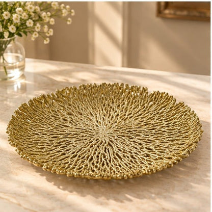 Coral metal tray in gold, dense radiating coral texture across a round dish, on a pale counter
