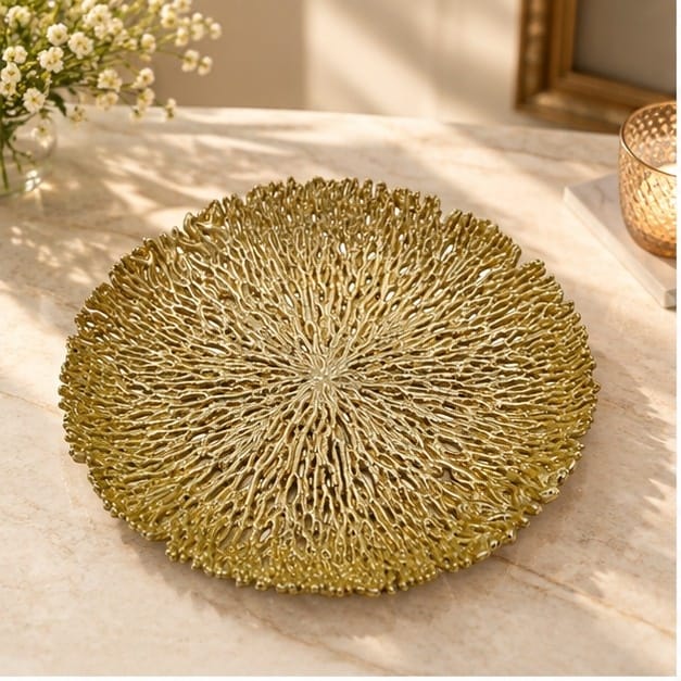 Coral metal tray in gold on a counter beside white blossom