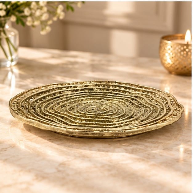 Spiral dosa tray in gold on a counter beside a lit candle