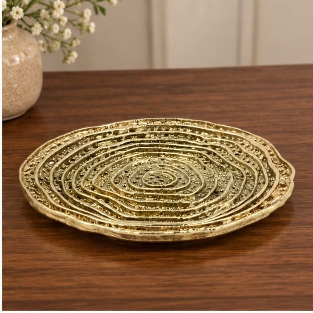Spiral dosa tray in gold on a dark wood table
