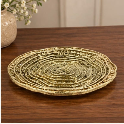 Spiral dosa tray in gold on a dark wood table