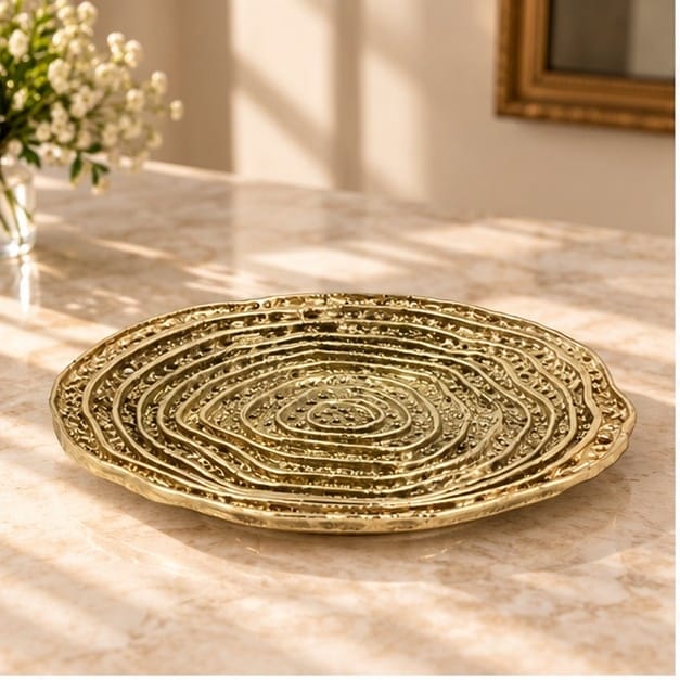Spiral dosa tray in gold, concentric ridges turning out from the centre, on a pale counter