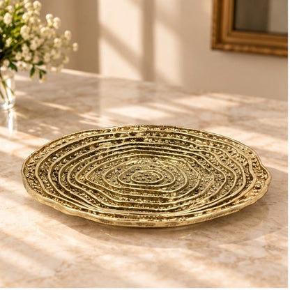 Spiral dosa tray in gold, concentric ridges turning out from the centre, on a pale counter