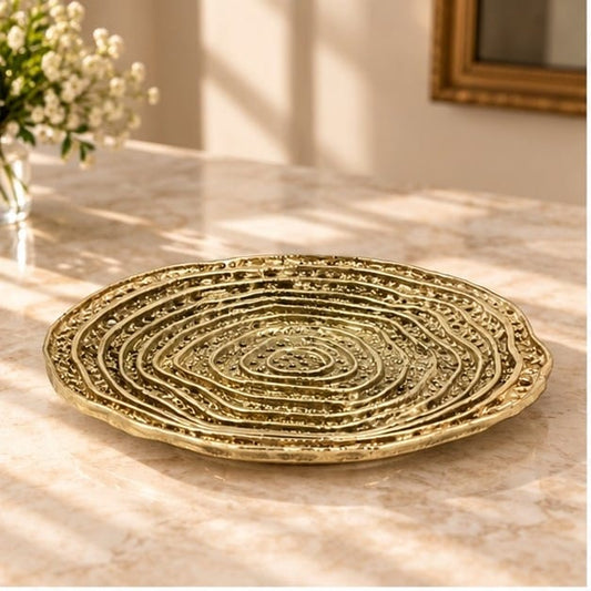 Spiral dosa tray in gold, concentric ridges turning out from the centre, on a pale counter