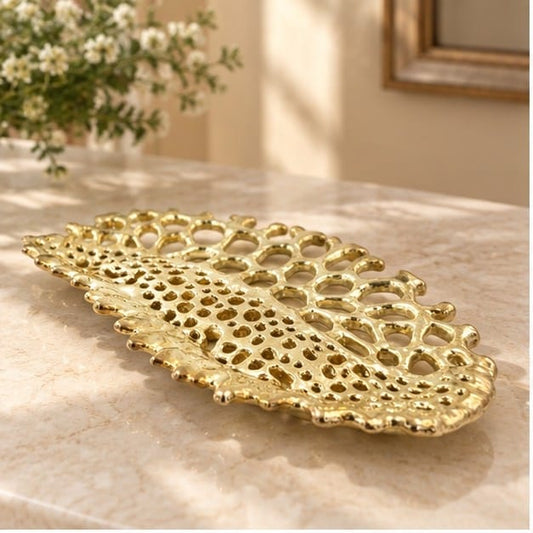 Fossil metal tray in gold, honeycomb texture in a long leaf shape, on a pale counter