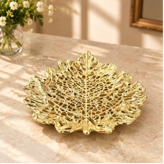 Skeletal leaf metal tray in gold, veins pierced right through the leaf, on a pale counter