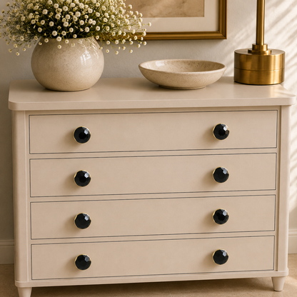 Eight small hematite knobs across four drawers of a cream chest of drawers