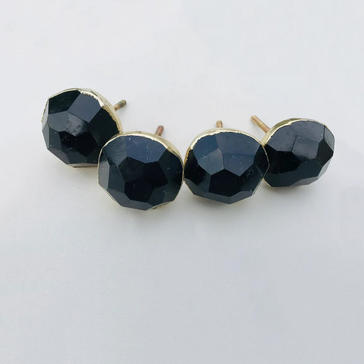 Four round faceted hematite knobs on white, near black and metallic